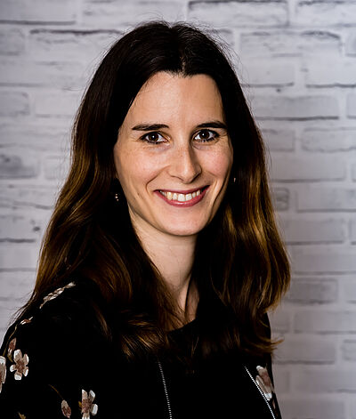 Porträt einer lächelnden Frau mit dunklem Haar Lächelnde Frau vor Ziegelwand